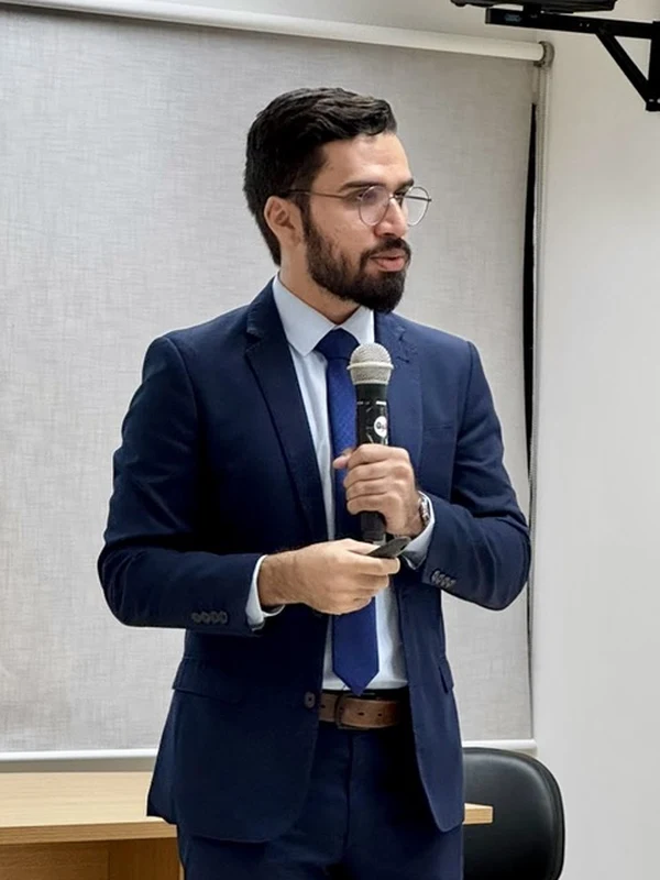 Leonardo Bandeira de terno azul, segurando um microfone durante uma palestra